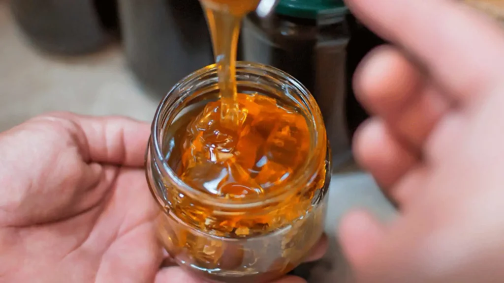 Miele dorato Piana Miele che cola in un vasetto di vetro, espressione della qualità e purezza del miele di Apicoltura Piana SpA | DiBi Group